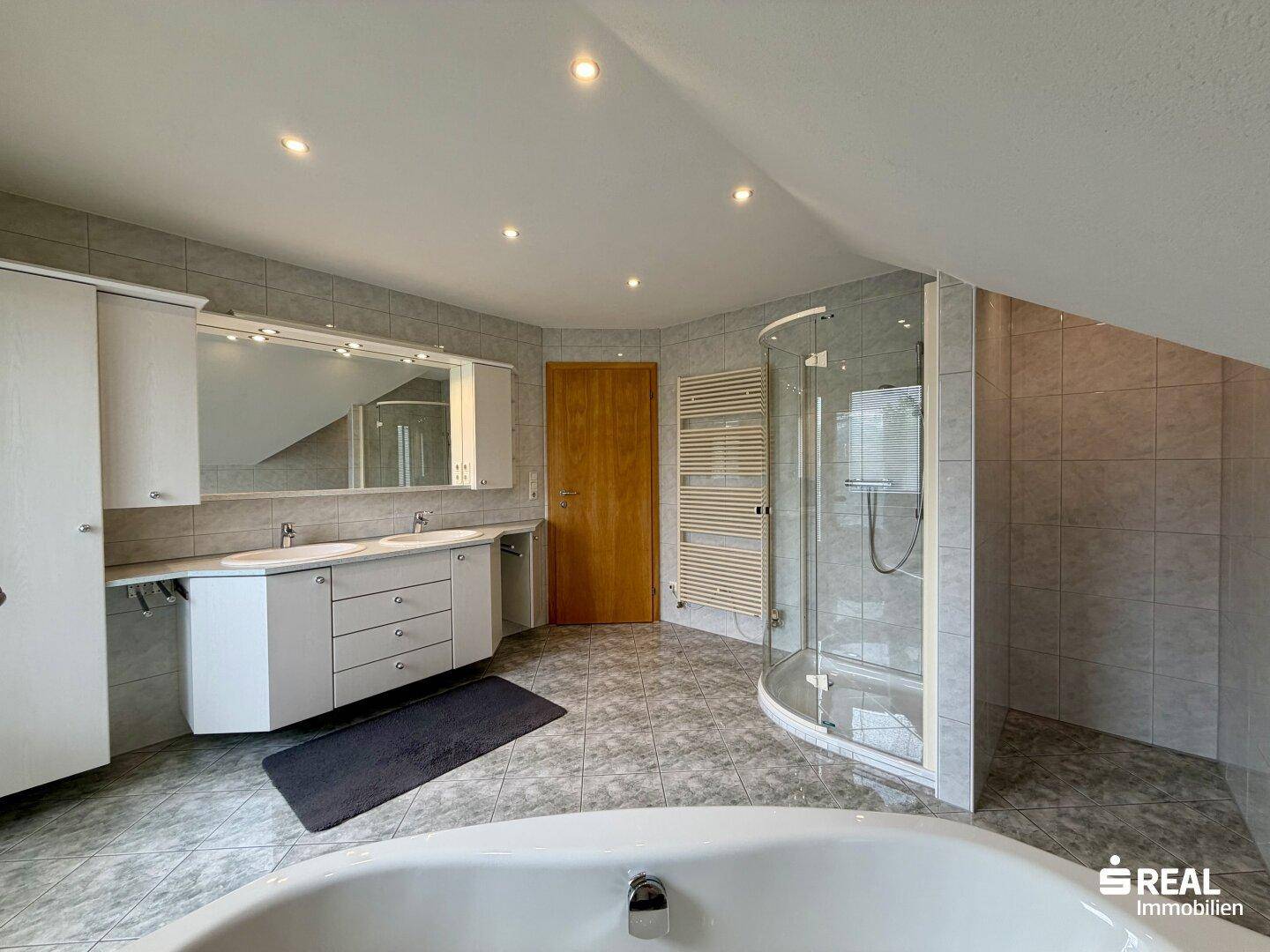 Modernes Badezimmer im Dachgeschoss mit Doppelwaschbecken, Dusche und beheiztem Handtuchhalter.