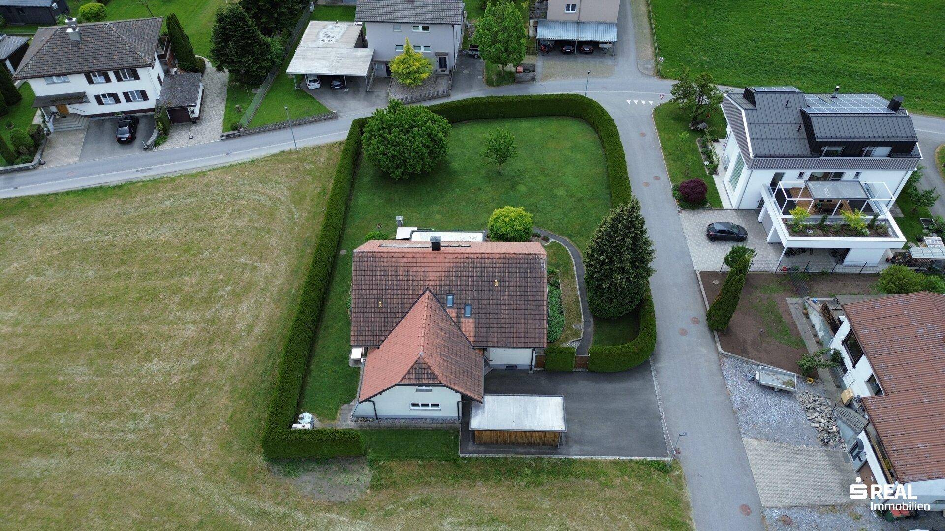 Übersichtliche Luftaufnahme des Hauses mit großem, eingezäunten Garten und umliegender Bebauung.