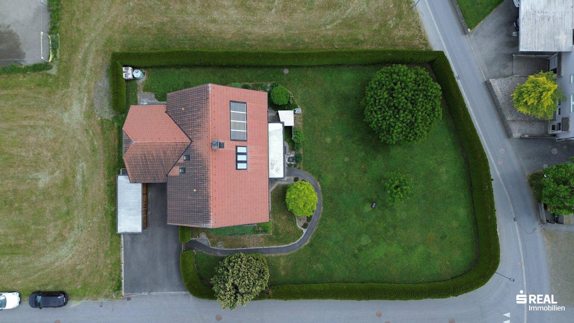 Vogelperspektive des Einfamilienhauses mit großem, umzäunten Garten und Baumbestand in ruhiger Lage.