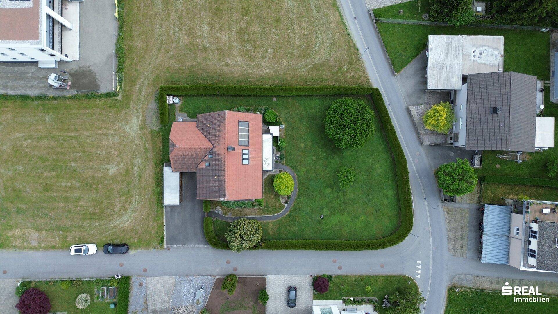 Draufsicht des Hauses und des Grundstücks mit Garten, Hecke und angrenzenden Straßen in der Nachbarschaft.