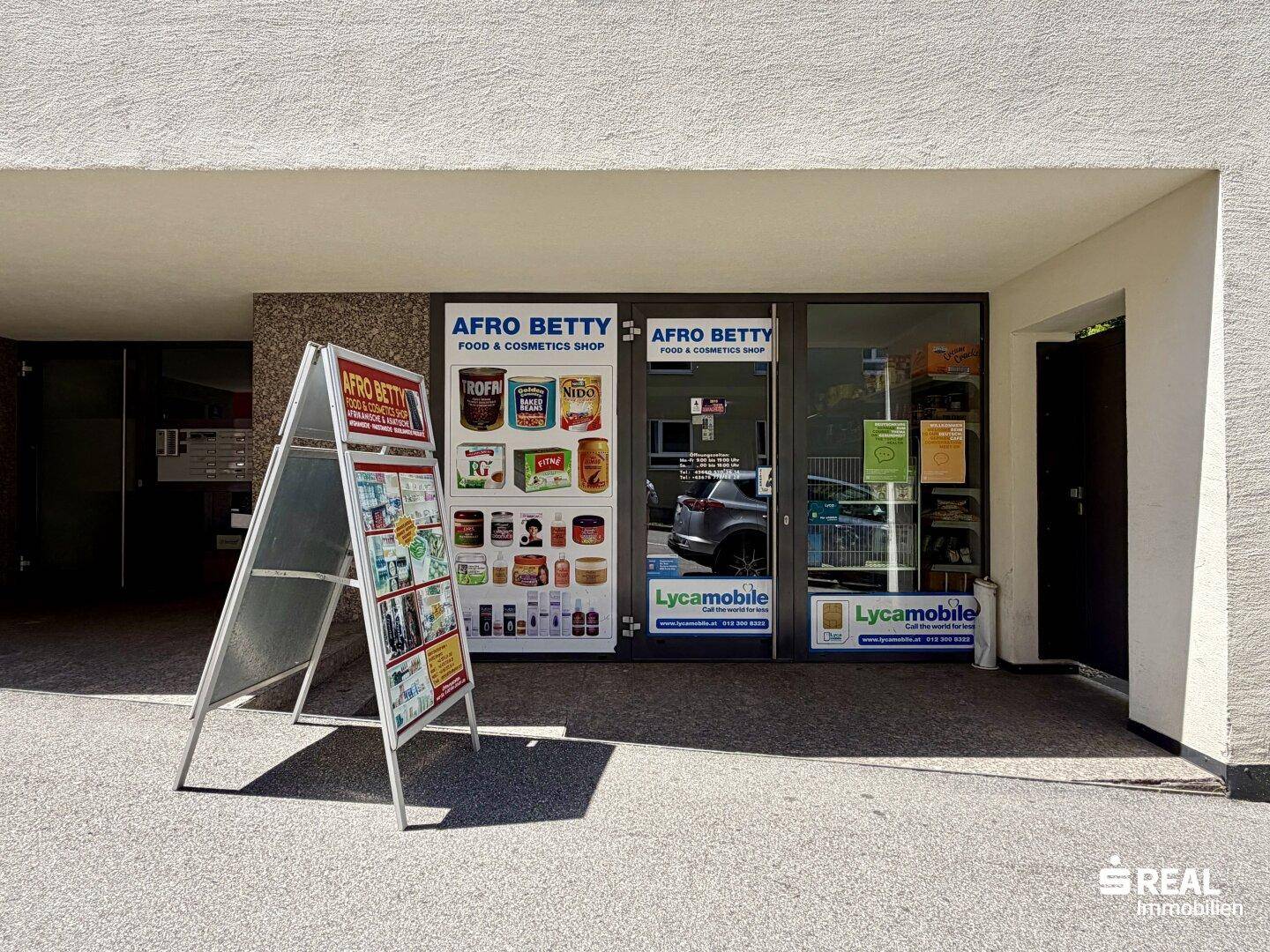 Eingangsbereich eines Lebensmittel- und Kosmetikgeschäfts im Erdgeschoss eines Gebäudes.
