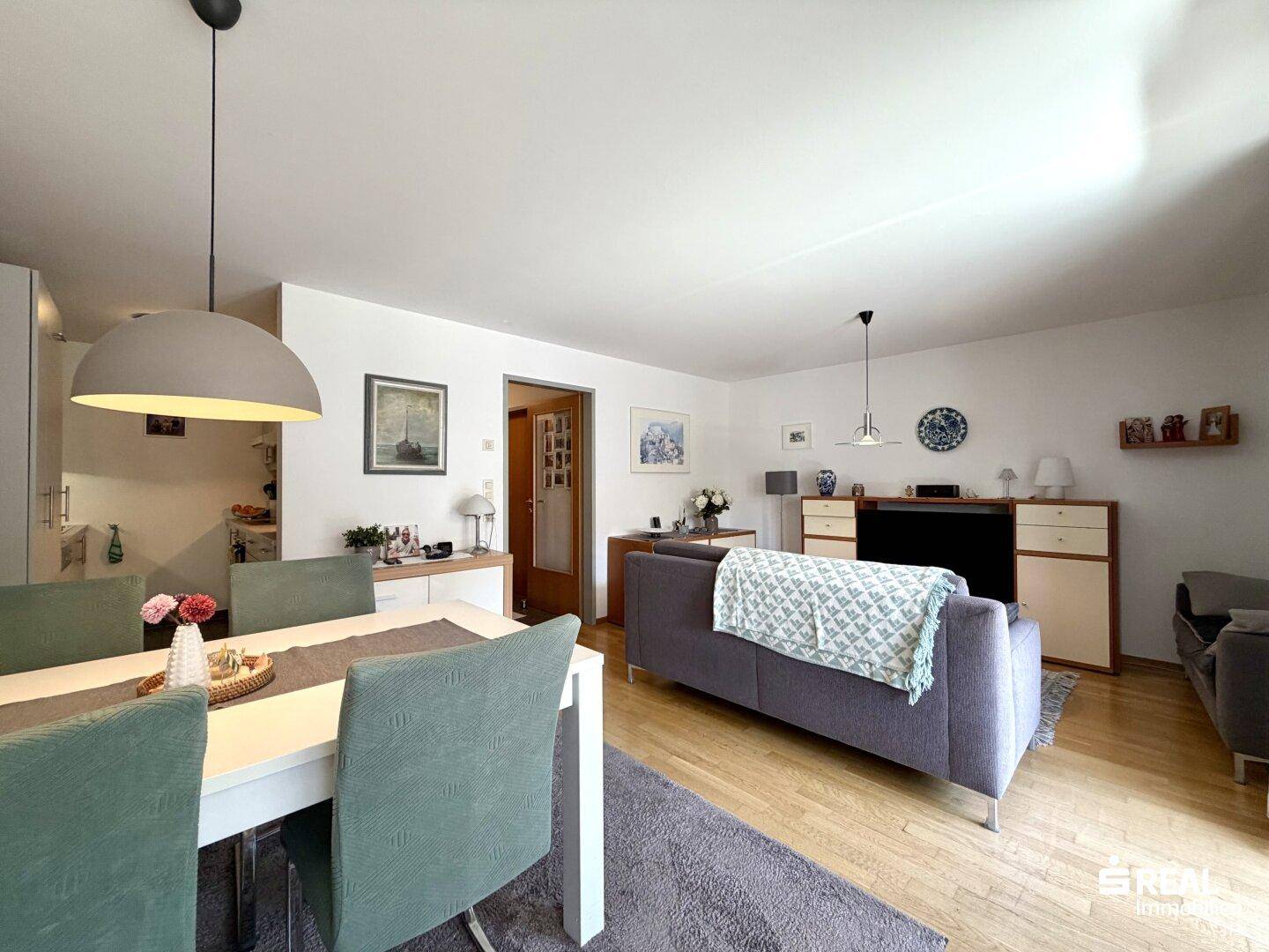 Heller Wohn-Essbereich mit Holzboden, Esstisch und Sofa, modern eingerichtet und gut gepflegt.