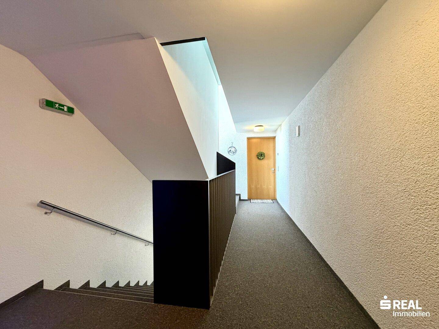 Heller Flur im Treppenhaus mit Treppe und Zugang zu den Wohnungen, gut beleuchtet.