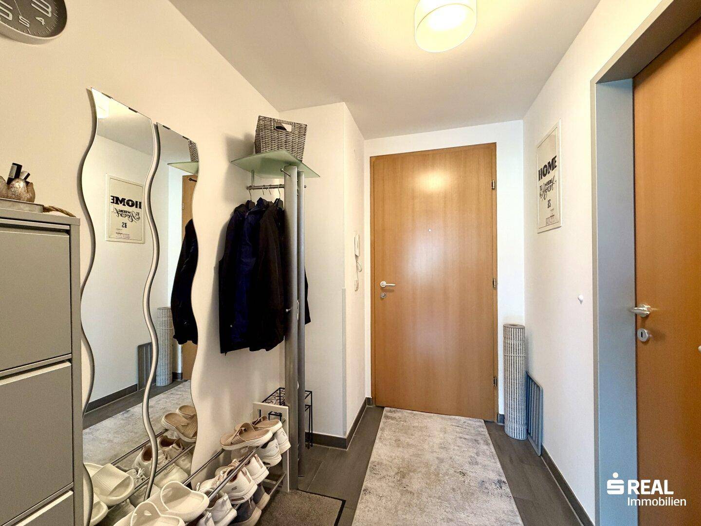 Eingangsbereich mit großem Spiegel, Schuhregal und Holztür, praktisch und einladend gestaltet.