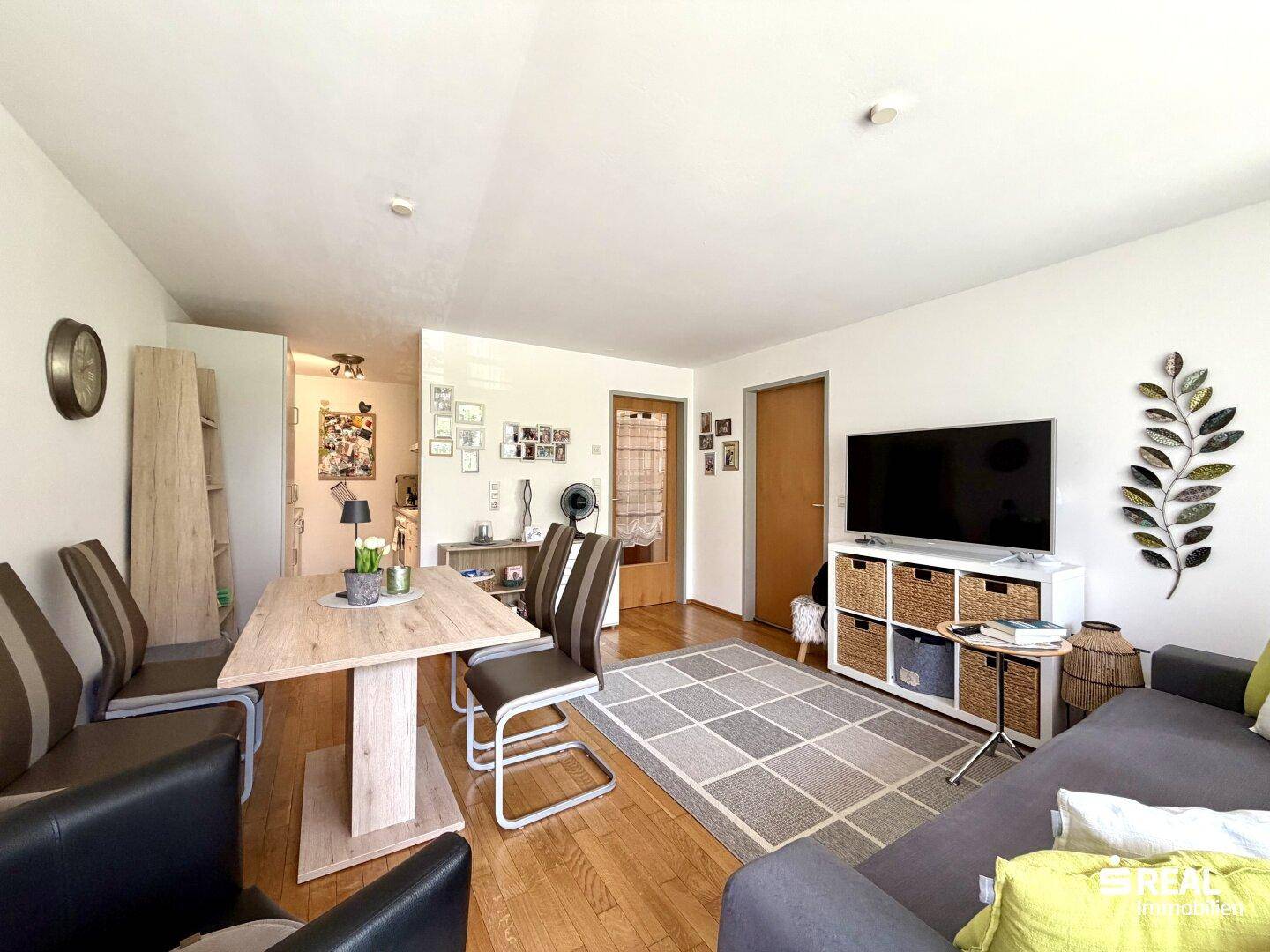 Heller Wohn-Essbereich mit Holzboden, Esstisch und Sofa, modern eingerichtet und einladend.