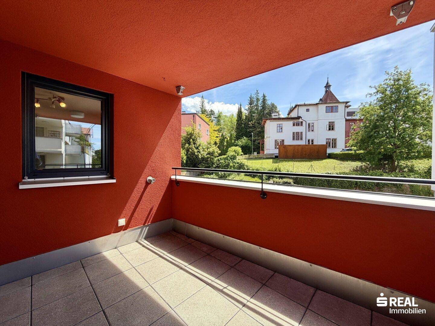 Geräumiger Balkon mit Fliesenboden und Blick auf die umliegende Wohnbebauung und viel Grün.