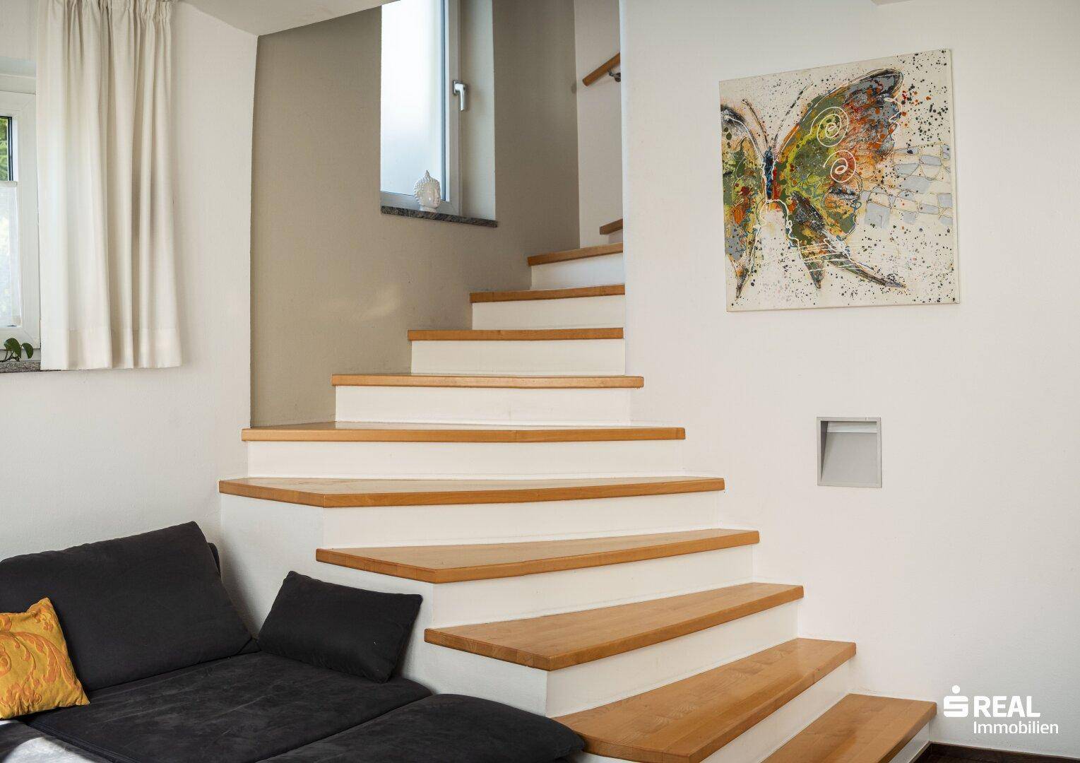 Helle Holztreppe mit weiß gestrichenen Stufen und moderner Kunst an der Wand.