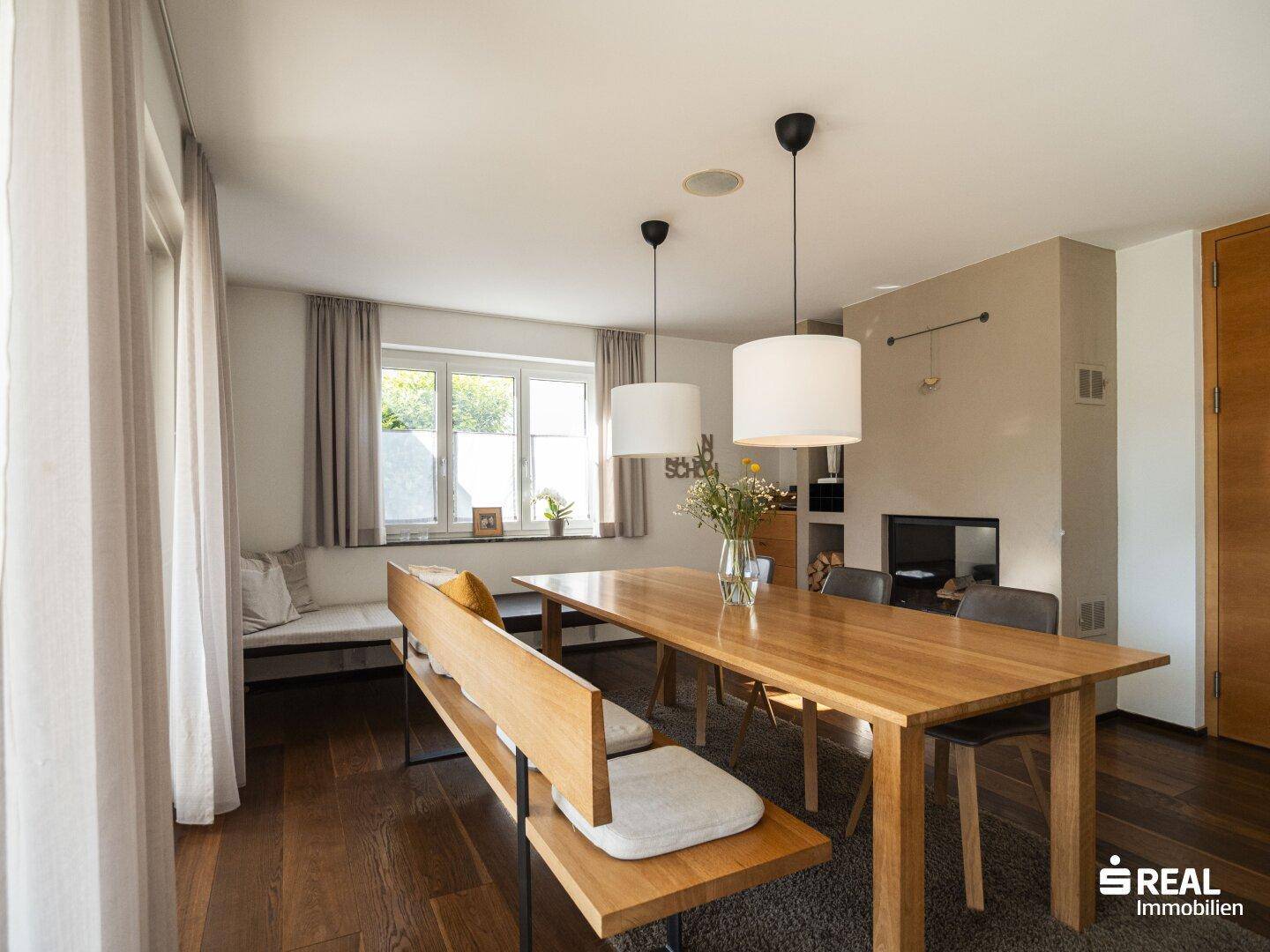 Geräumiger Essbereich mit Holztisch, Sitzbank und Blick auf den integrierten Kamin.