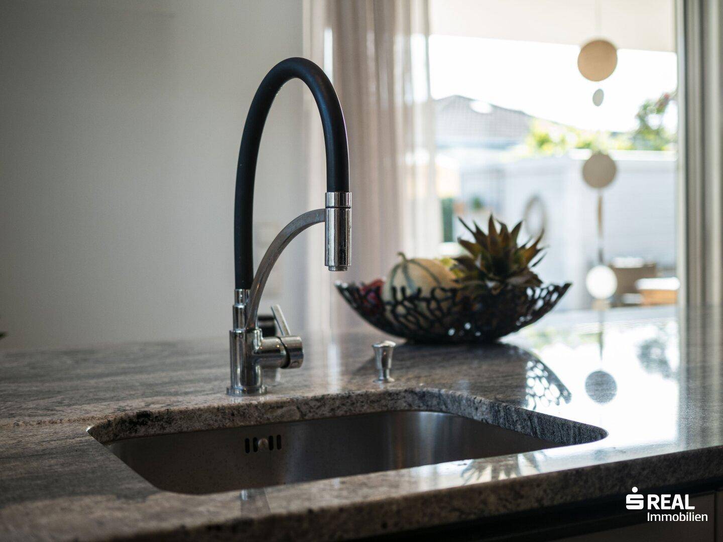 Moderner Wasserhahn und Spülbecken in der Kücheninsel mit Granitarbeitsplatte.