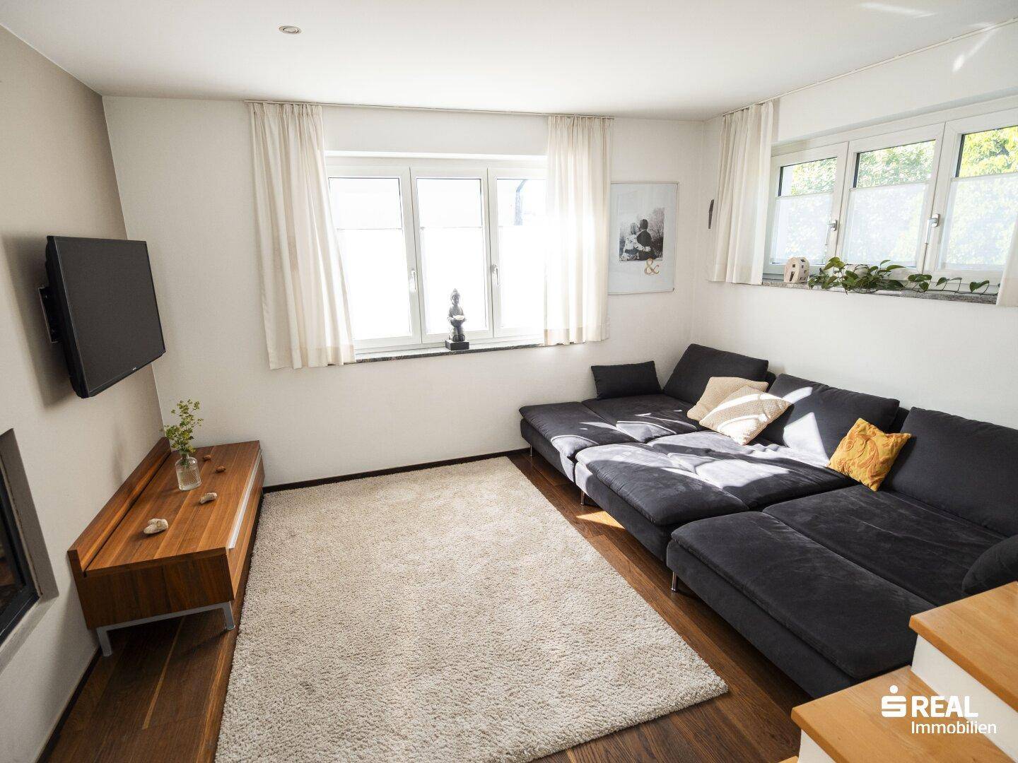Gemütliches Wohnzimmer mit großem Sofa, Kamin und Holzboden.
