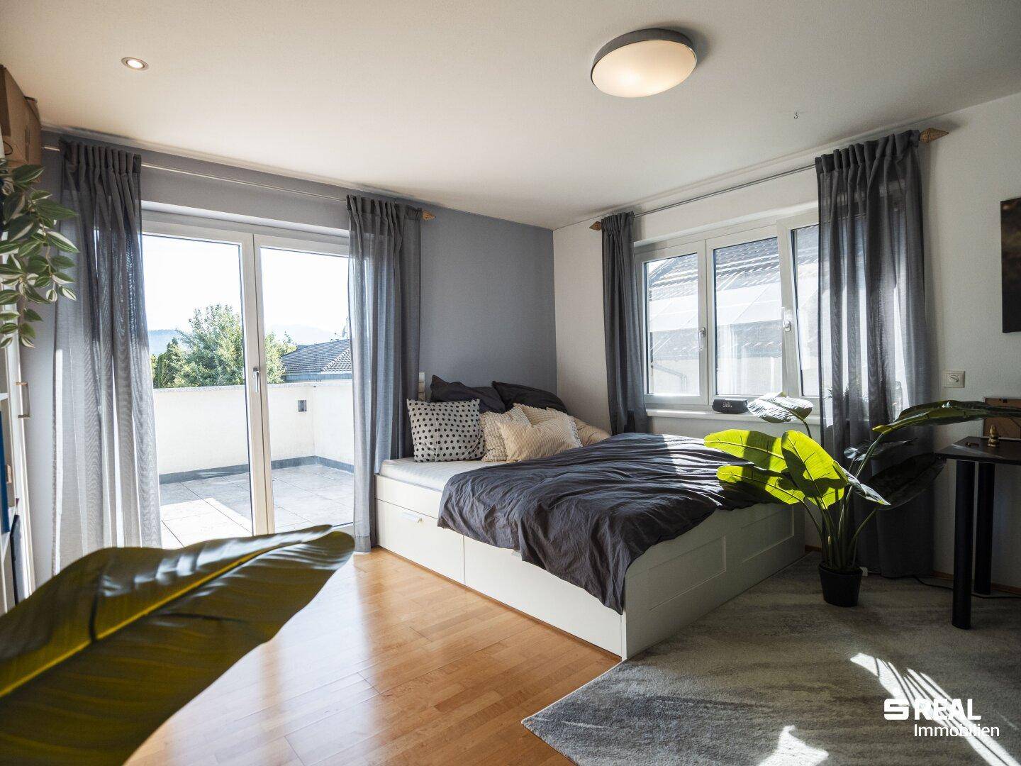 Schlafzimmer mit Zugang zur Terrasse, Holzboden und viel Tageslicht.