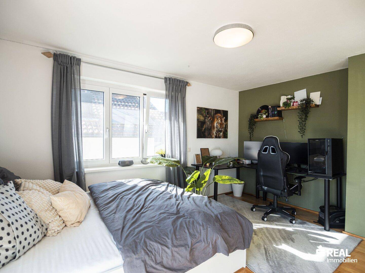 Modernes Schlafzimmer mit Schreibtischbereich, Holzboden und grüner Akzentwand.
