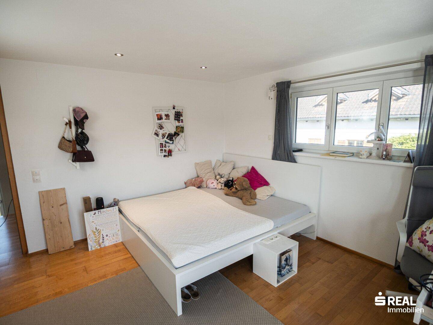 Helles Schlafzimmer mit Holzboden und großem Fenster, ideal für Kinder oder Gäste.