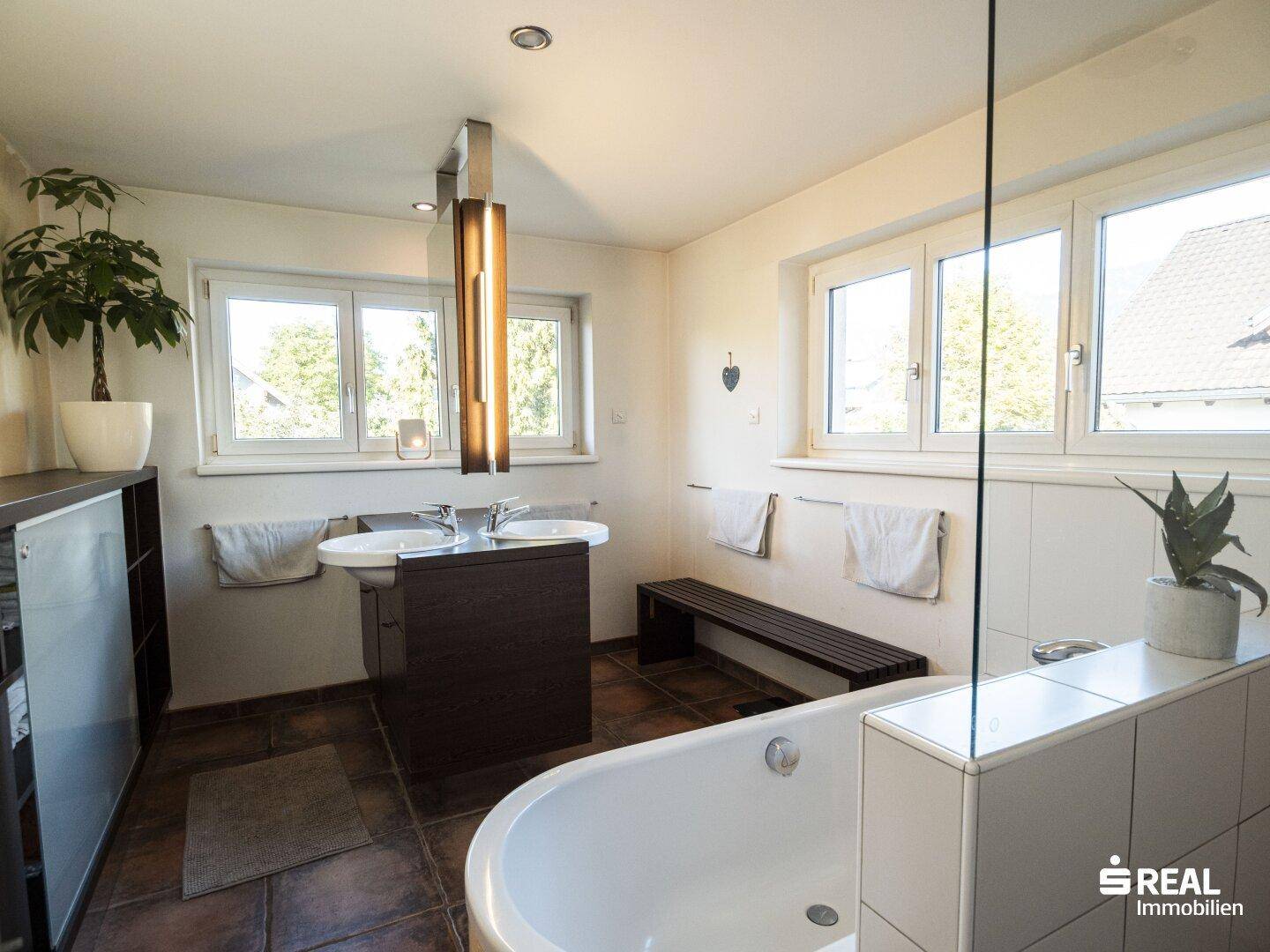 Modernes Badezimmer mit Badewanne, Doppelwaschbecken und großem Fenster.