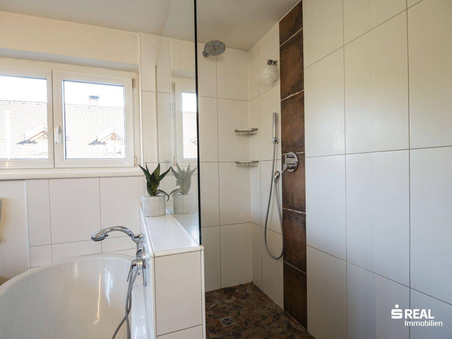 Modernes Badezimmer mit Badewanne und begehbarer Dusche, hell gefliest.