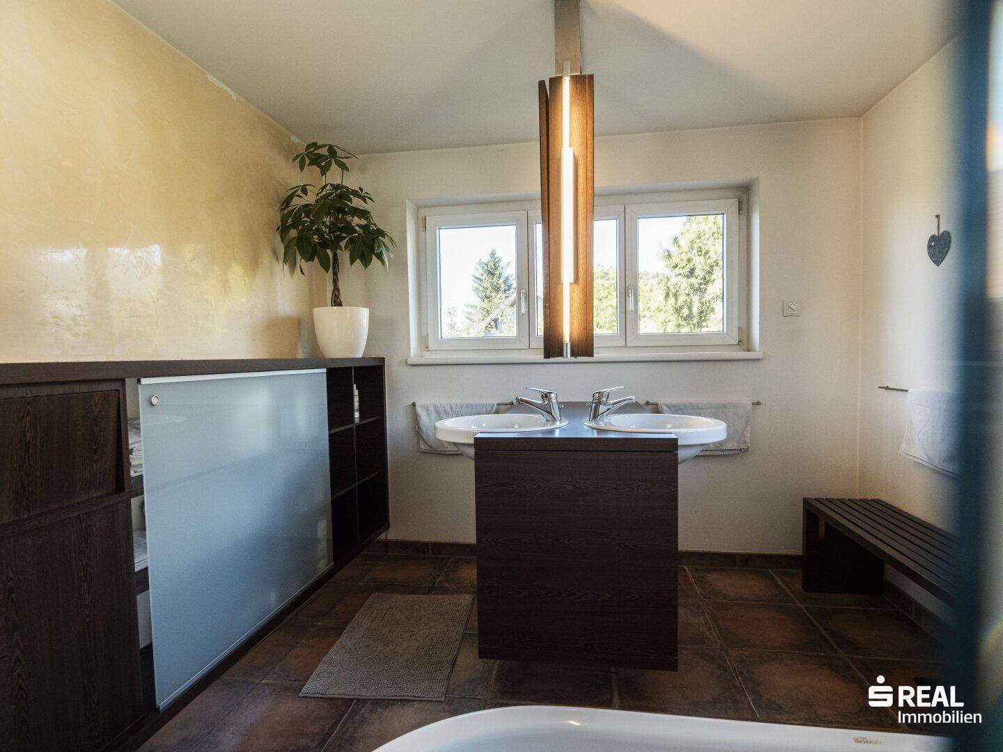 Stilvolles Badezimmer mit Doppelwaschbecken, Badewanne und natürlichem Lichteinfall.