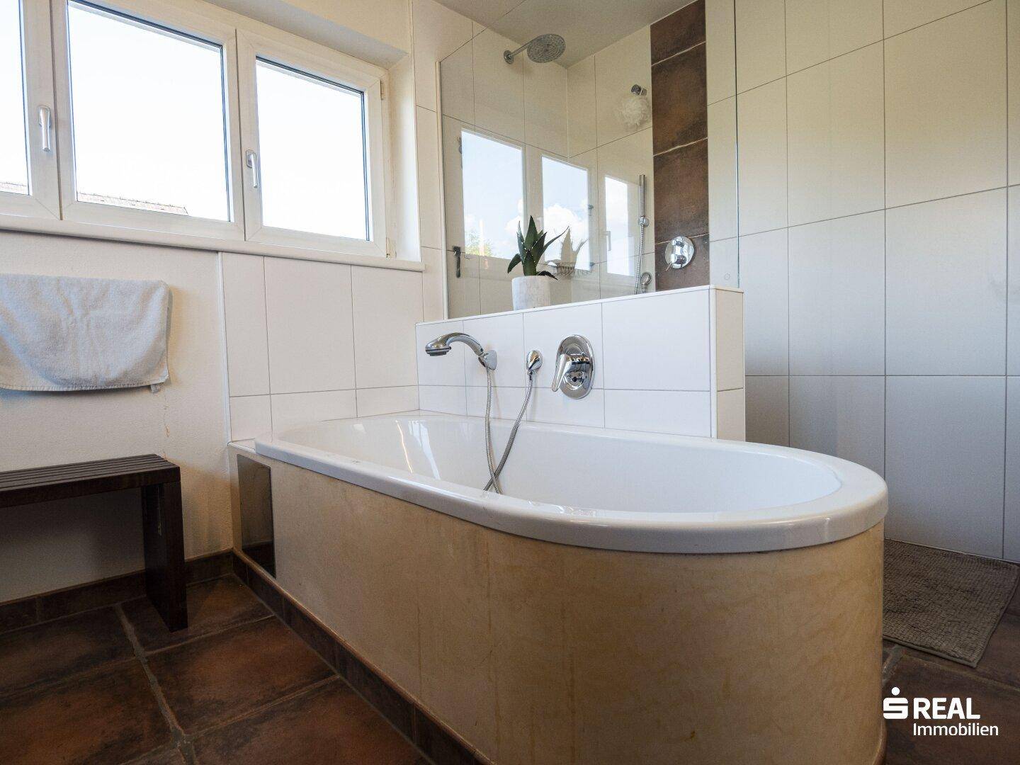Helles Badezimmer mit Badewanne und Duschbereich, ausgestattet mit modernen Armaturen.