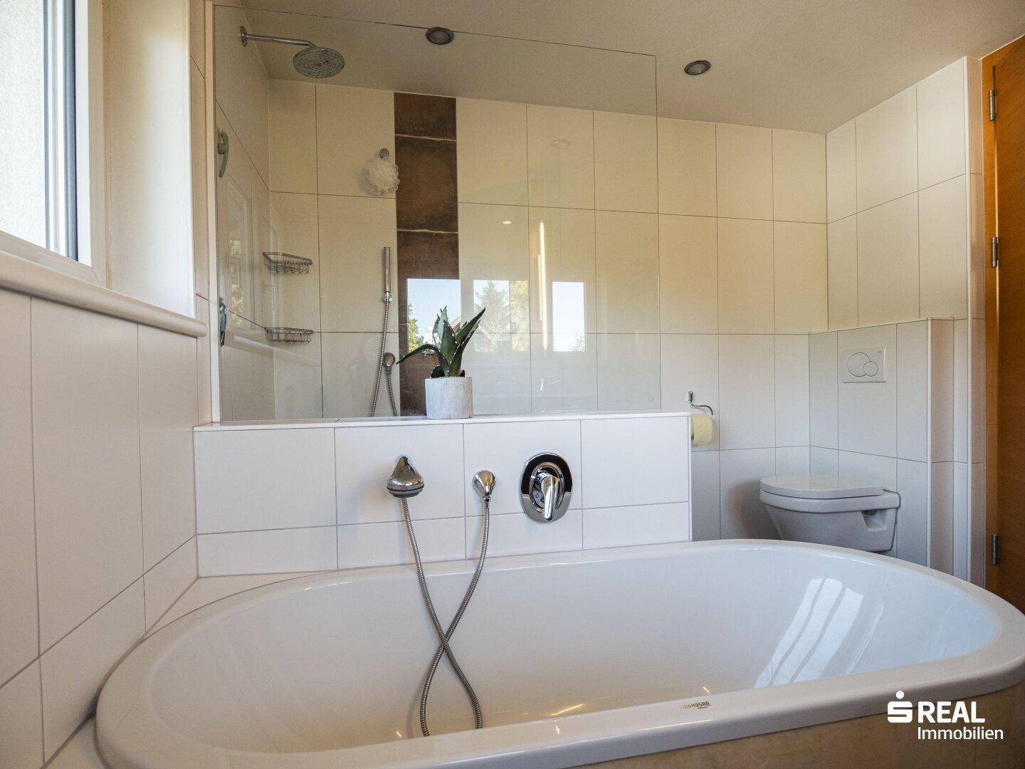 Badezimmer mit Badewanne, Dusche und Toilette, hell gefliest und funktional.