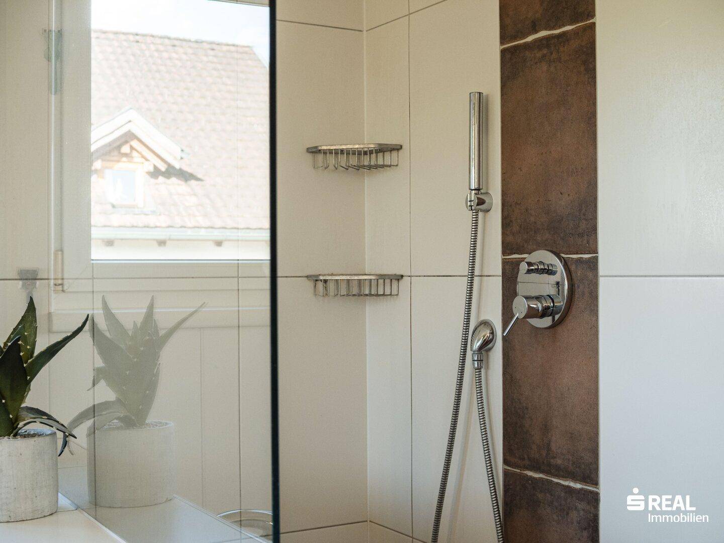 Duschbereich im Badezimmer mit modernen Fliesen und Regendusche.