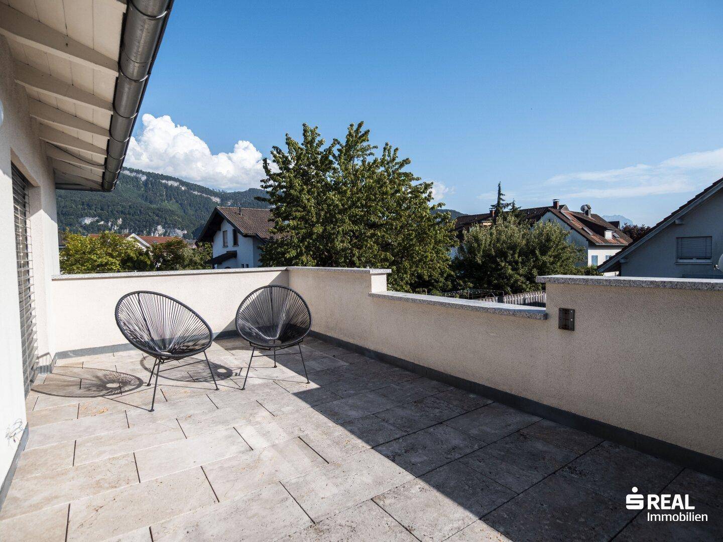 Geräumige Dachterrasse mit modernen Sitzgelegenheiten und Bergblick.