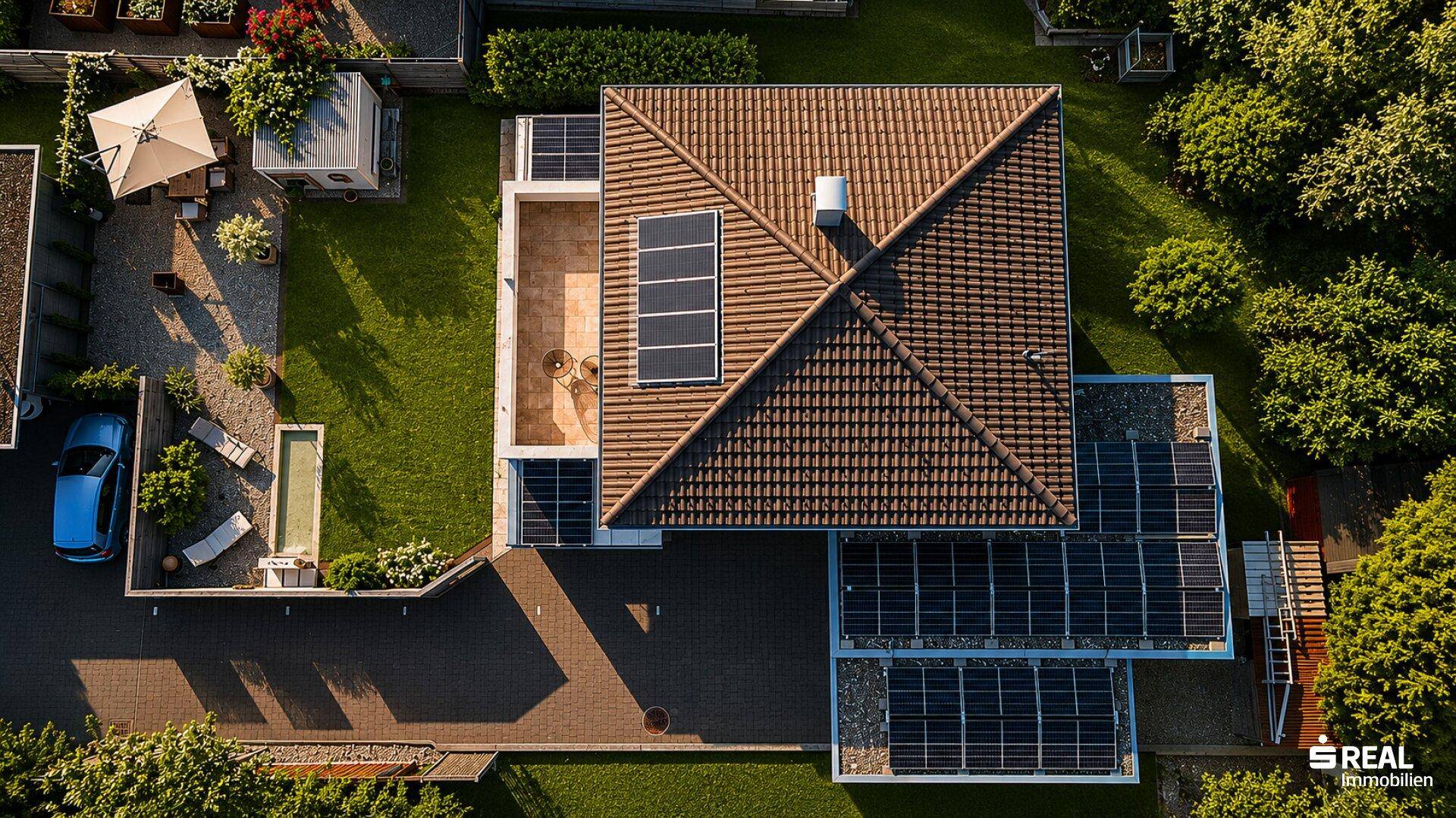 Luftaufnahme eines Einfamilienhauses mit Satteldach, Photovoltaikanlage und gepflegtem Garten.
