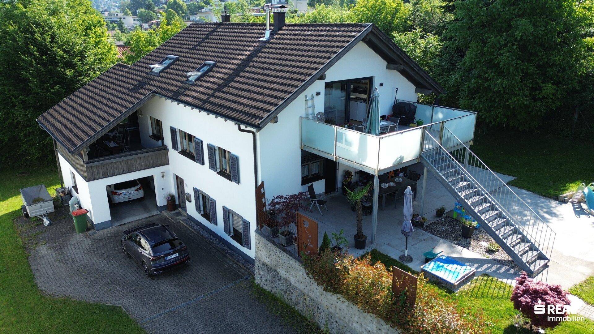 Detaillierte Luftaufnahme des Hauses mit Balkonen, Außentreppe und gepflegtem Gartenbereich.