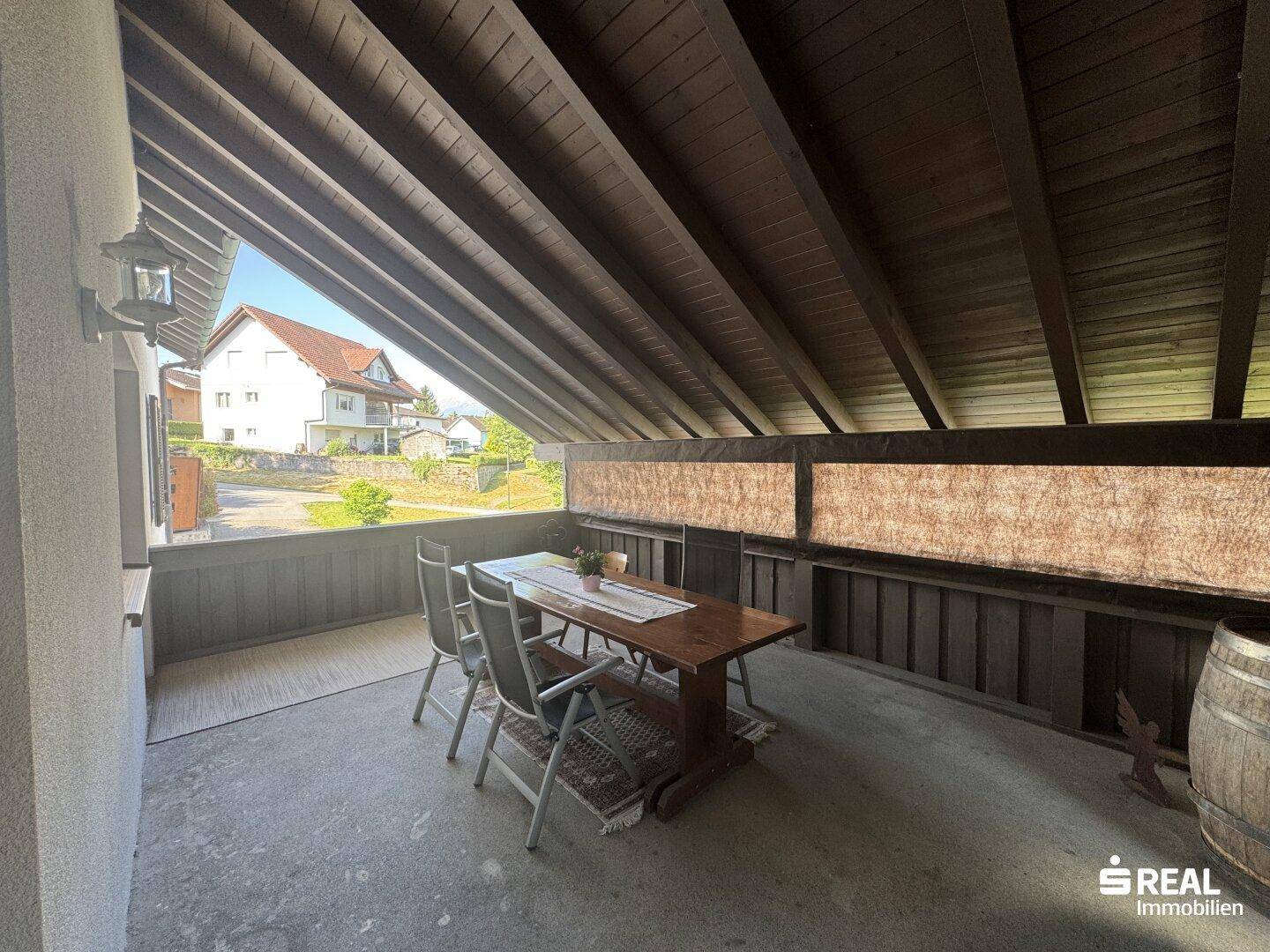 Überdachte Loggia mit Holztisch und Stühlen, ideal für Mahlzeiten im Freien.