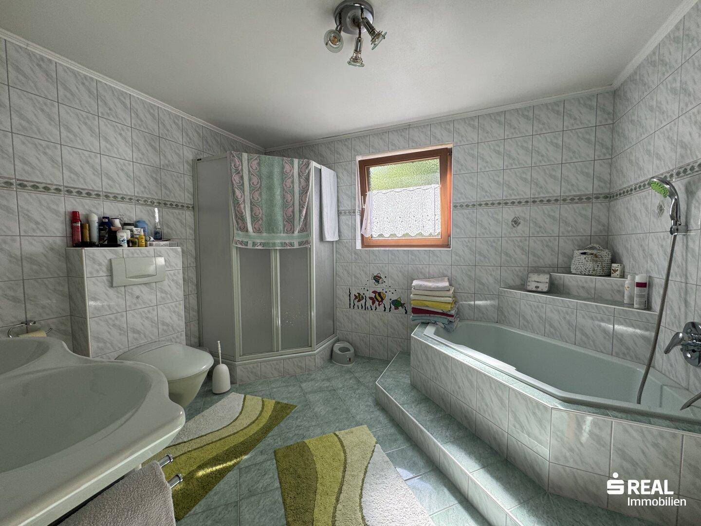 Badezimmer im 80er-Jahre-Stil mit Eckbadewanne, Dusche und Fenster.