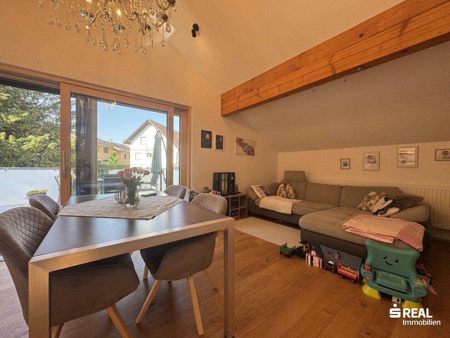 Gemütlicher Wohnbereich mit Sofa, Esstisch und großem Schiebefenster zum Außenbereich.