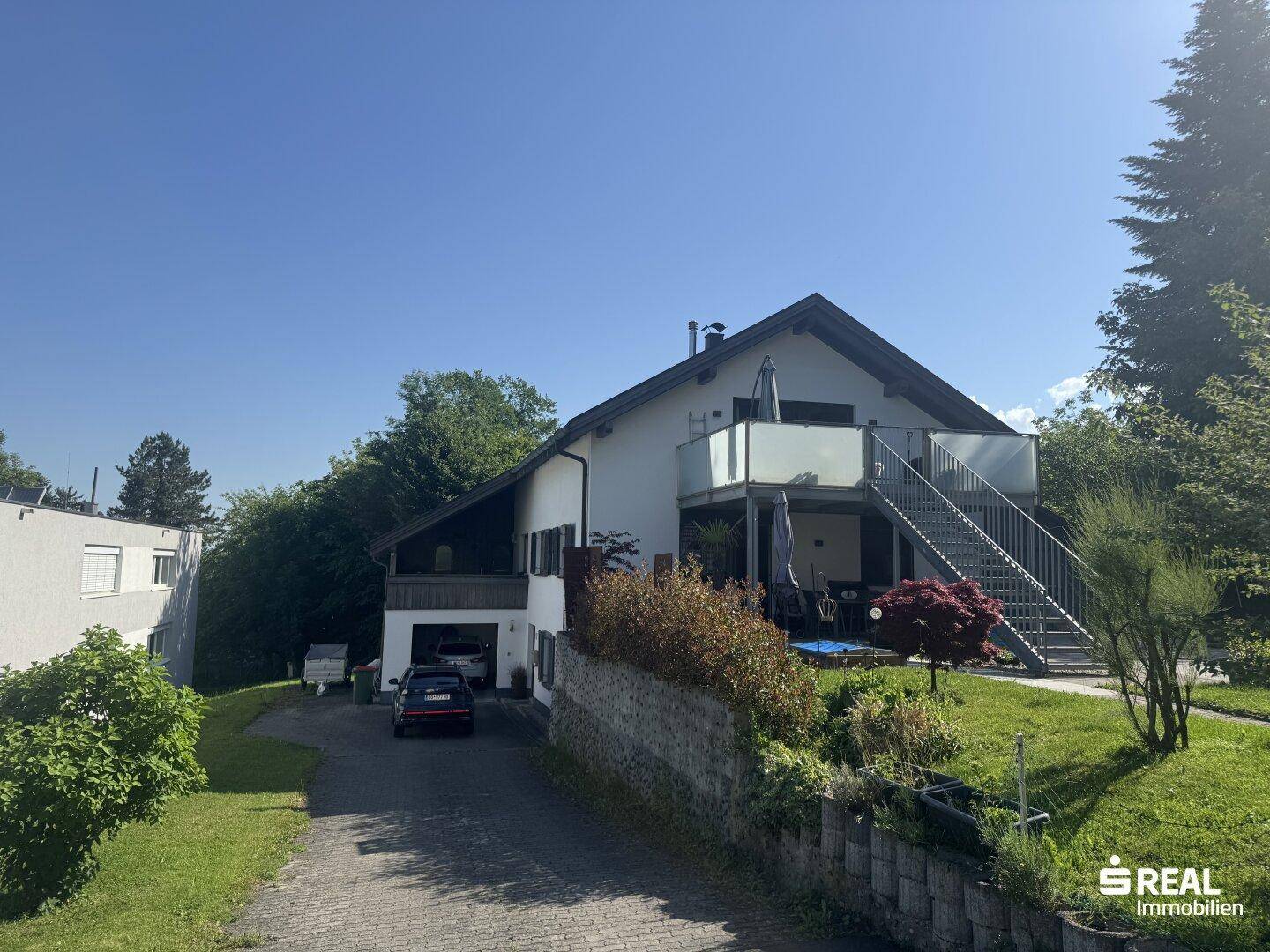 Ansicht des Einfamilienhauses von der Auffahrt mit Garten und umliegender Natur.