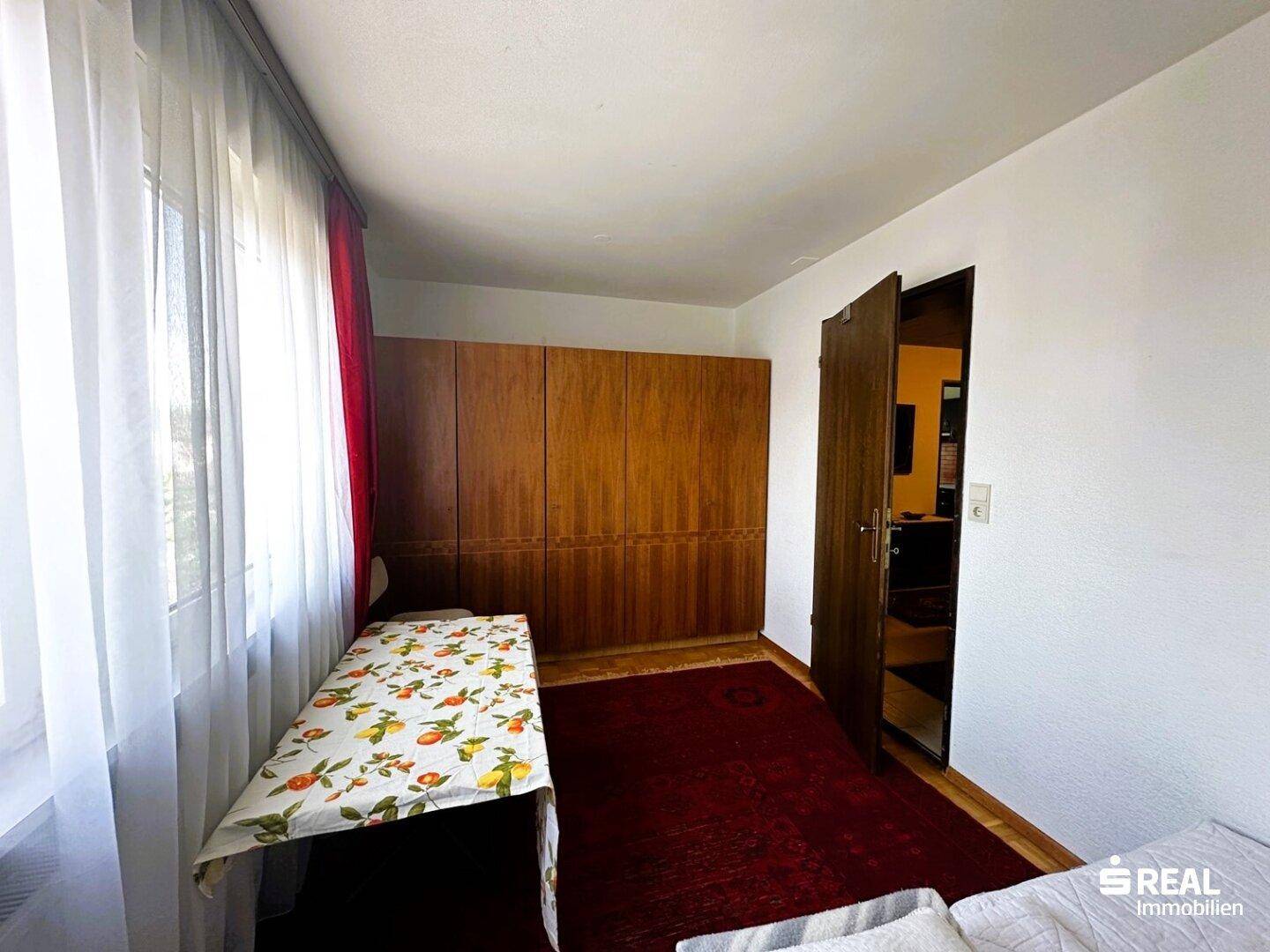 Schlafzimmer mit integrierten Holzschränken und einem roten Teppichboden, der Gemütlichkeit verleiht.