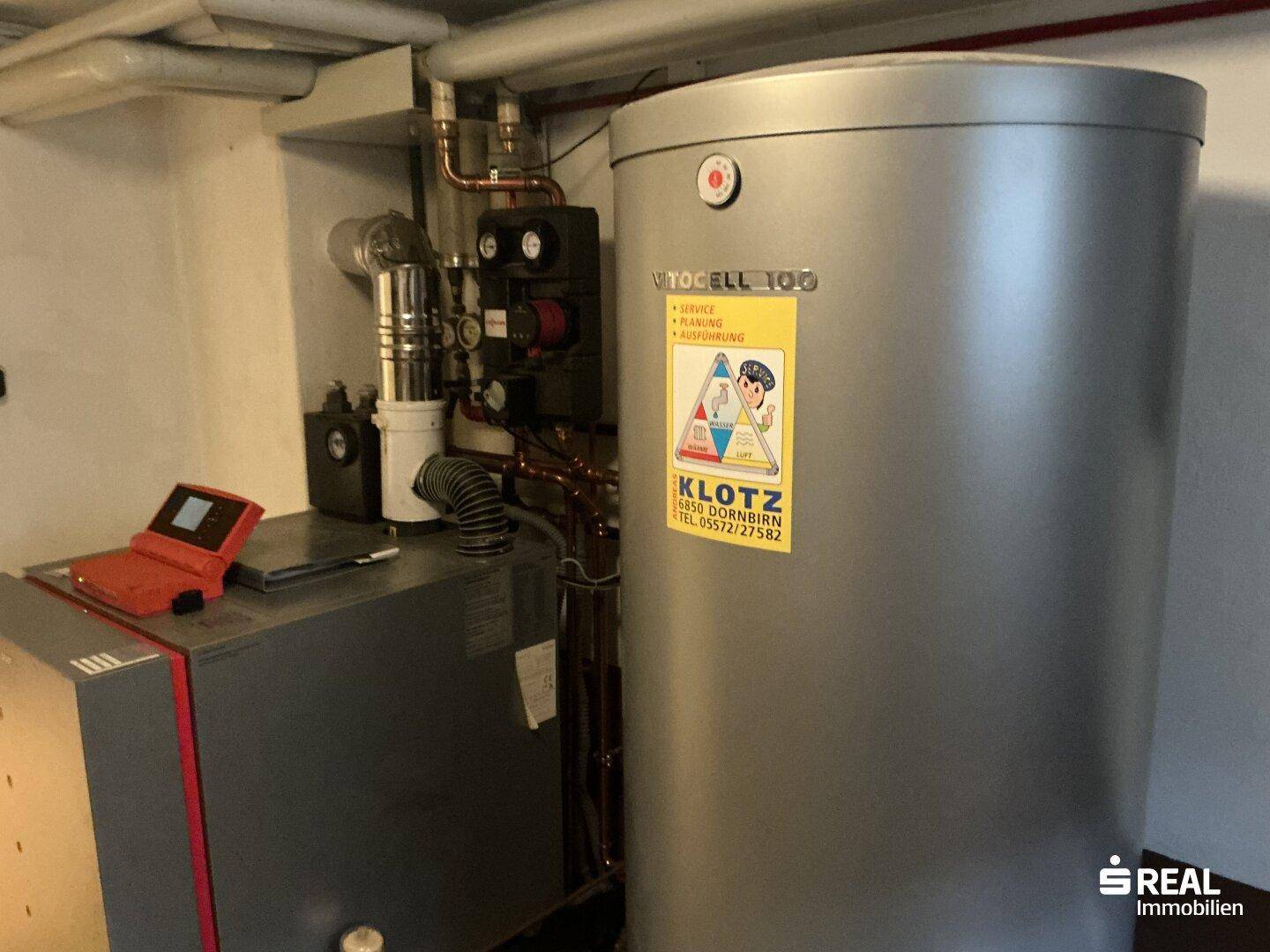 Heizungsraum mit großem Warmwasserspeicher und Heizungsanlage im Kellerbereich.