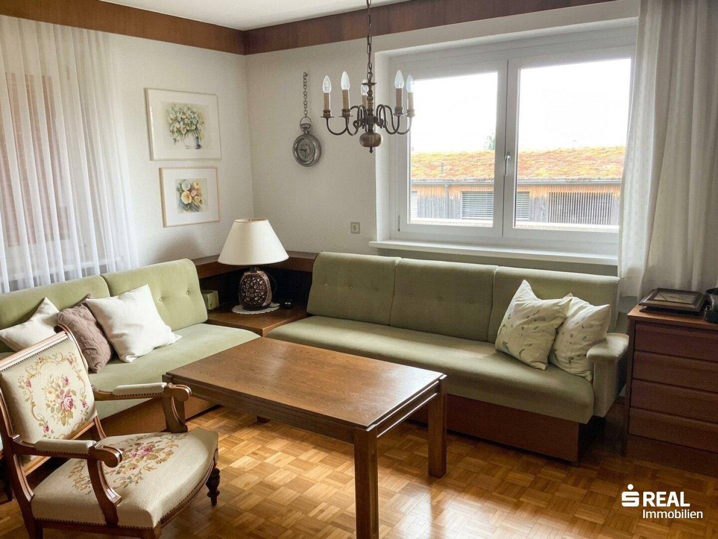 Gemütliches Wohnzimmer mit zwei Sofas, Couchtisch und Parkettboden, hell durch große Fenster.