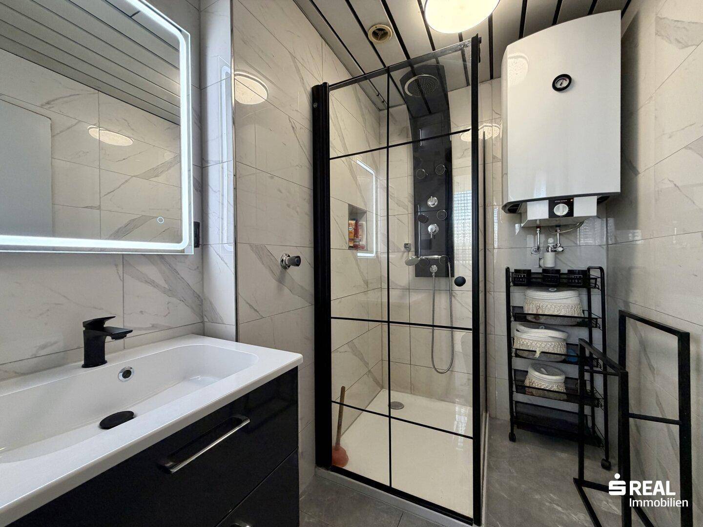 Modernes Badezimmer mit Duschkabine, Waschtisch und eleganten Marmorfliesen.