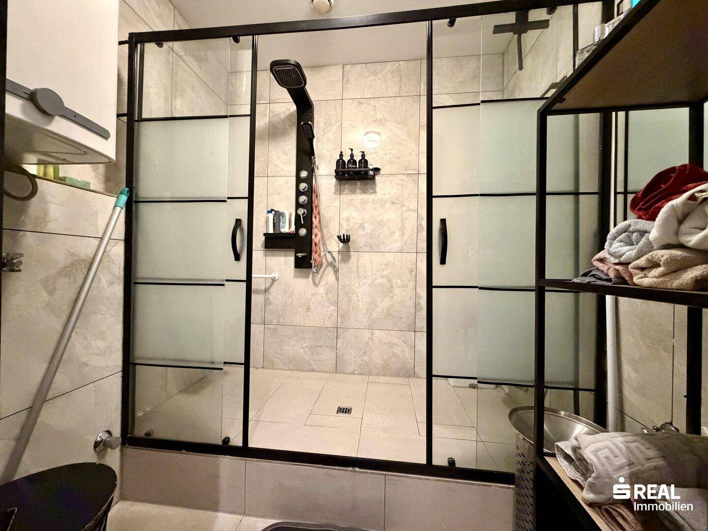Modernes Badezimmer mit großer Duschkabine, Regendusche und hellen Fliesen.