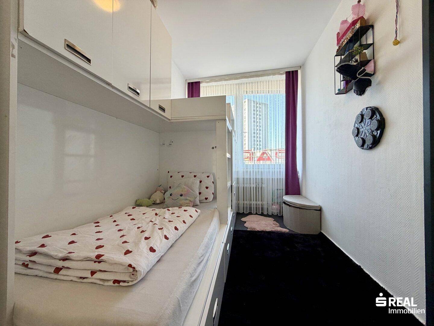 Kinderzimmer mit Etagenbett, hellem Fenster und farbigen Vorhängen, ideal für Geschwister.