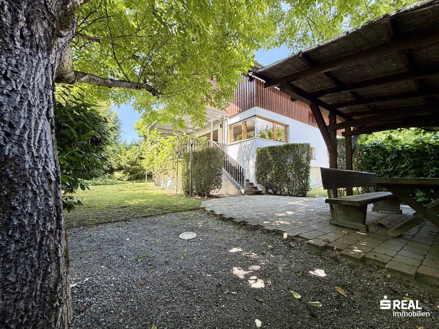Gemütlicher Gartenbereich mit überdachtem Sitzplatz und Blick auf das Haus.
