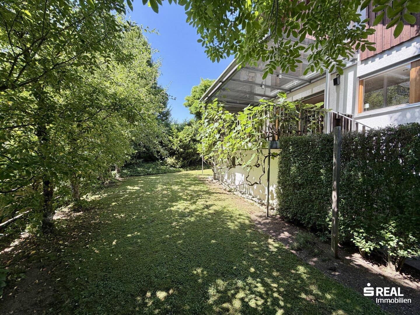 Großer, gepflegter Garten mit Rasenfläche und üppiger Vegetation rund um das Haus.