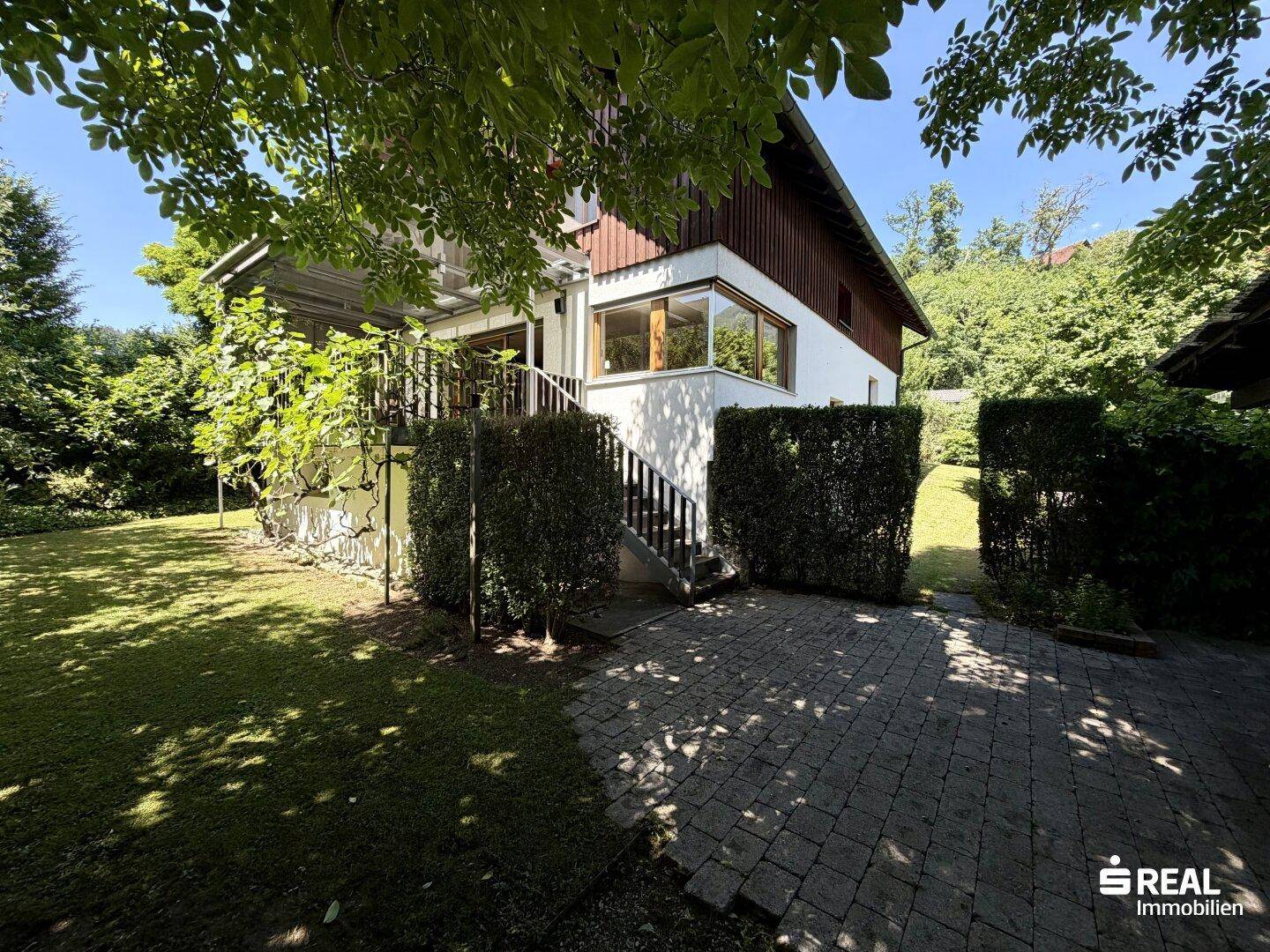 Seitliche Ansicht des Hauses mit Außentreppe, Terrasse und weitläufigem Garten.