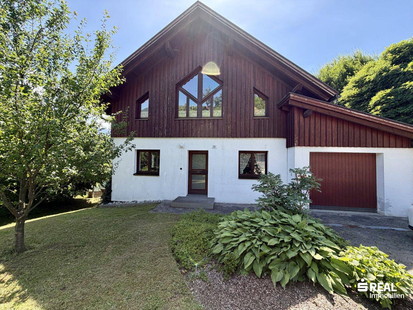 Vorderansicht des Hauses mit Satteldach, Holzfassade und gepflegtem Vorgarten.