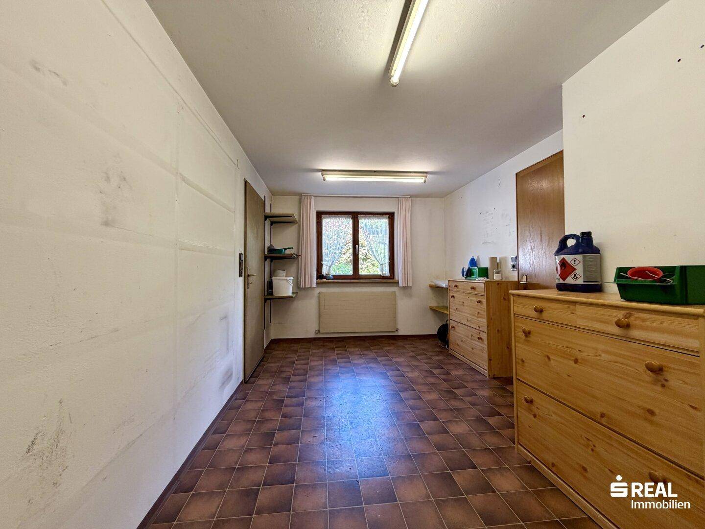 Kellerraum mit Fliesenboden, Fenster und Regalen für Lagerzwecke.
