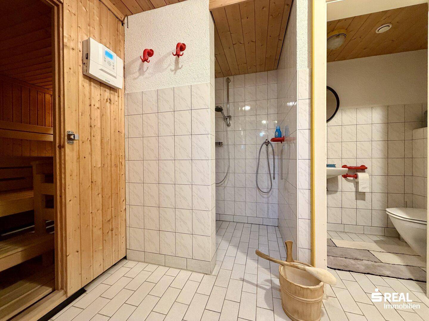 Badezimmer mit integrierter Sauna, Duschbereich und separatem WC.