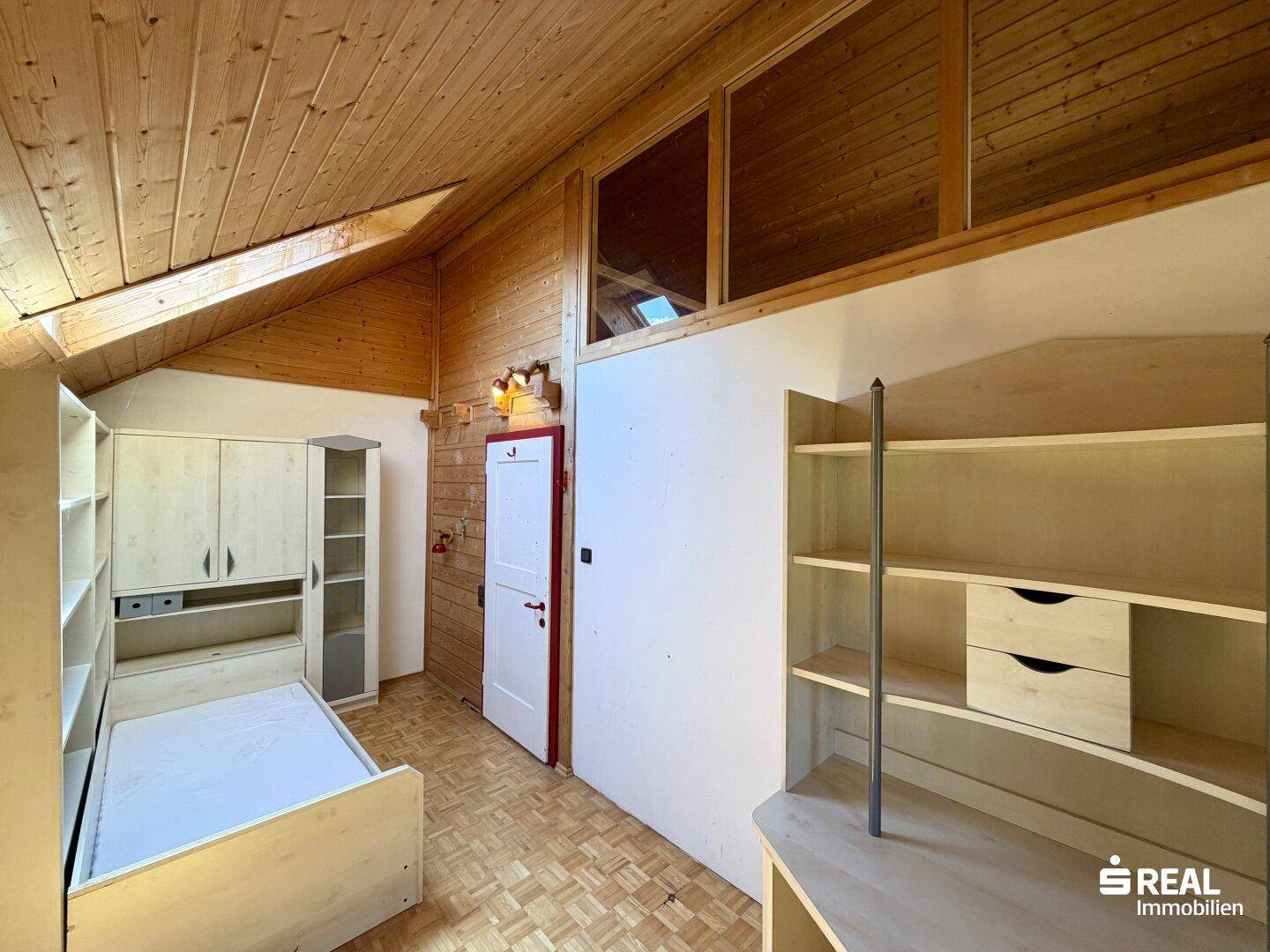 Gemütliches Schlafzimmer im Dachgeschoss mit Holzdecke, Einzelbett und Einbauschränken.
