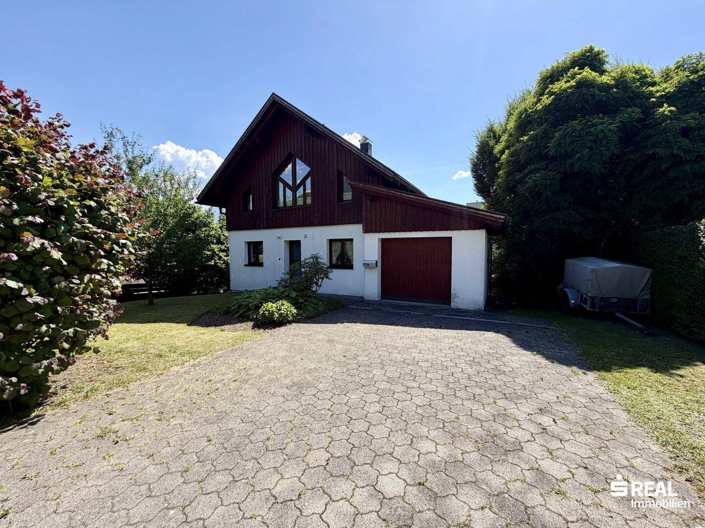 Vorderansicht des Einfamilienhauses mit Satteldach, Garage und gepflasterter Auffahrt.