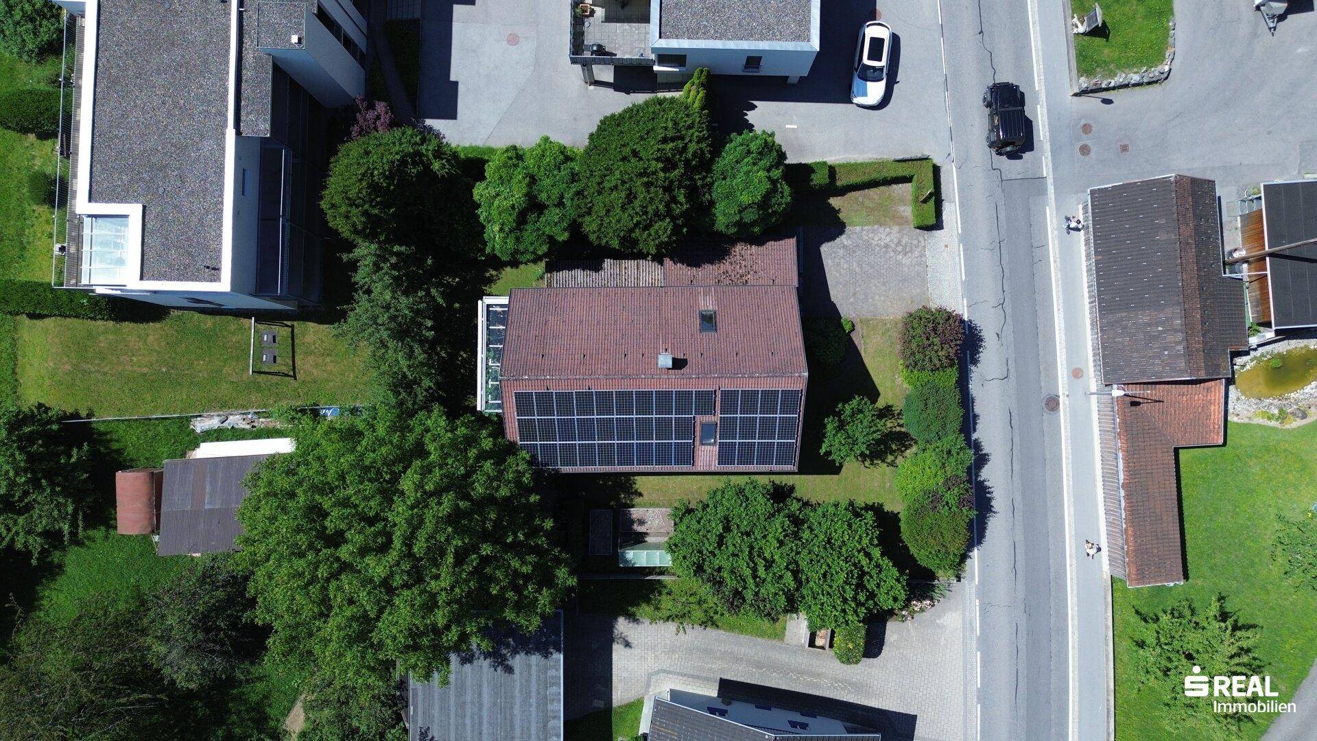 Vogelperspektive des Hauses mit Photovoltaikanlage auf dem Dach, Garten und Zufahrt.