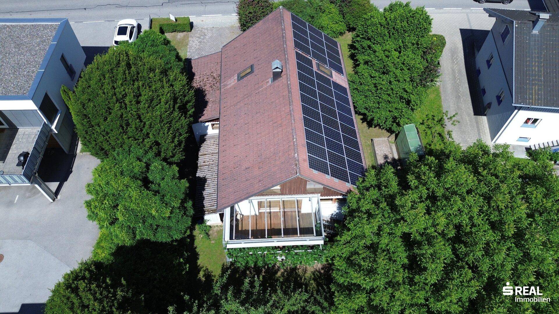 Luftaufnahme des Hauses mit Photovoltaikanlage, Wintergarten und umgebenden Bäumen.