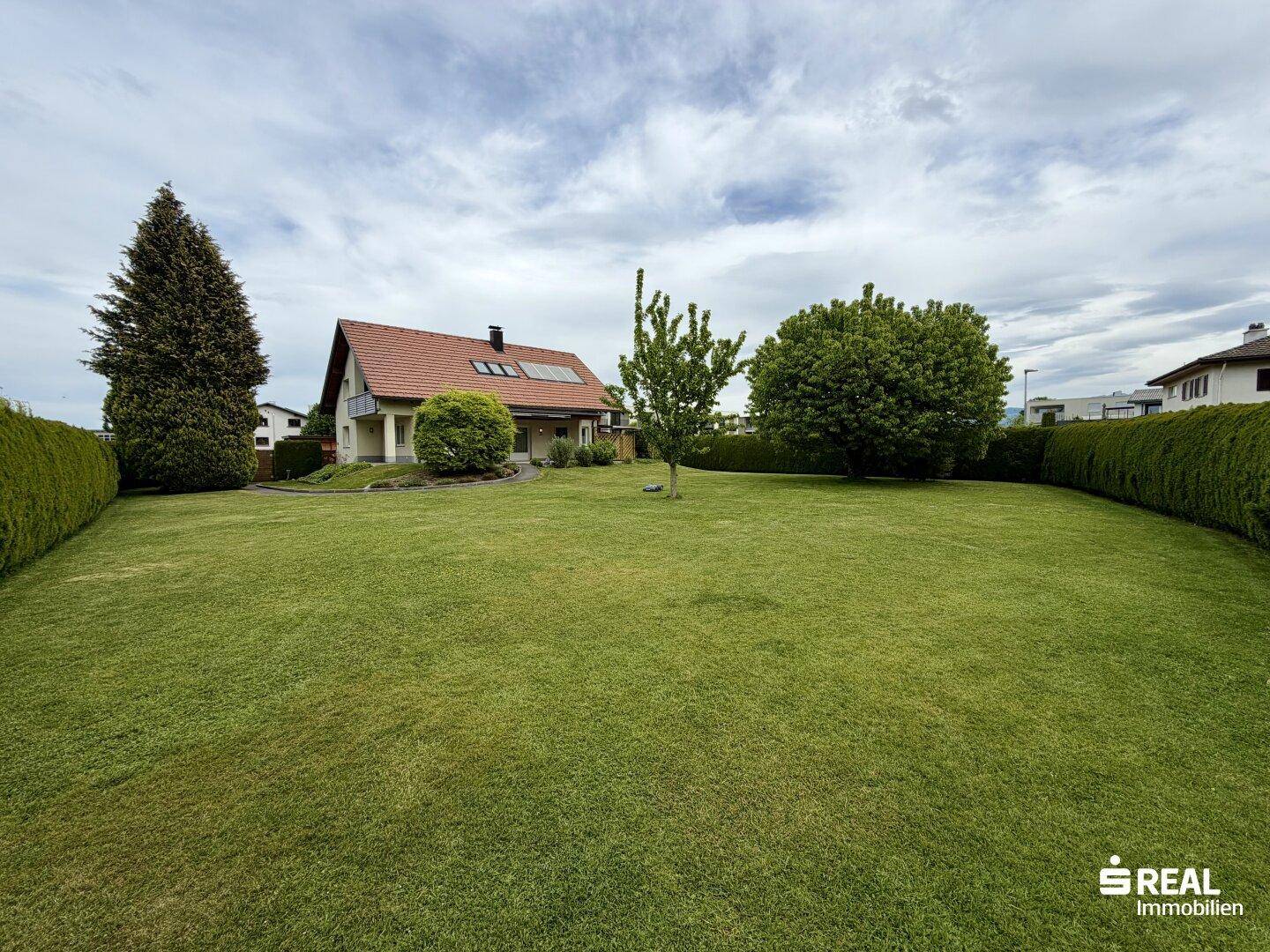 Großer, gepflegter Gartenbereich mit altem Baumbestand und dem Einfamilienhaus im Hintergrund.