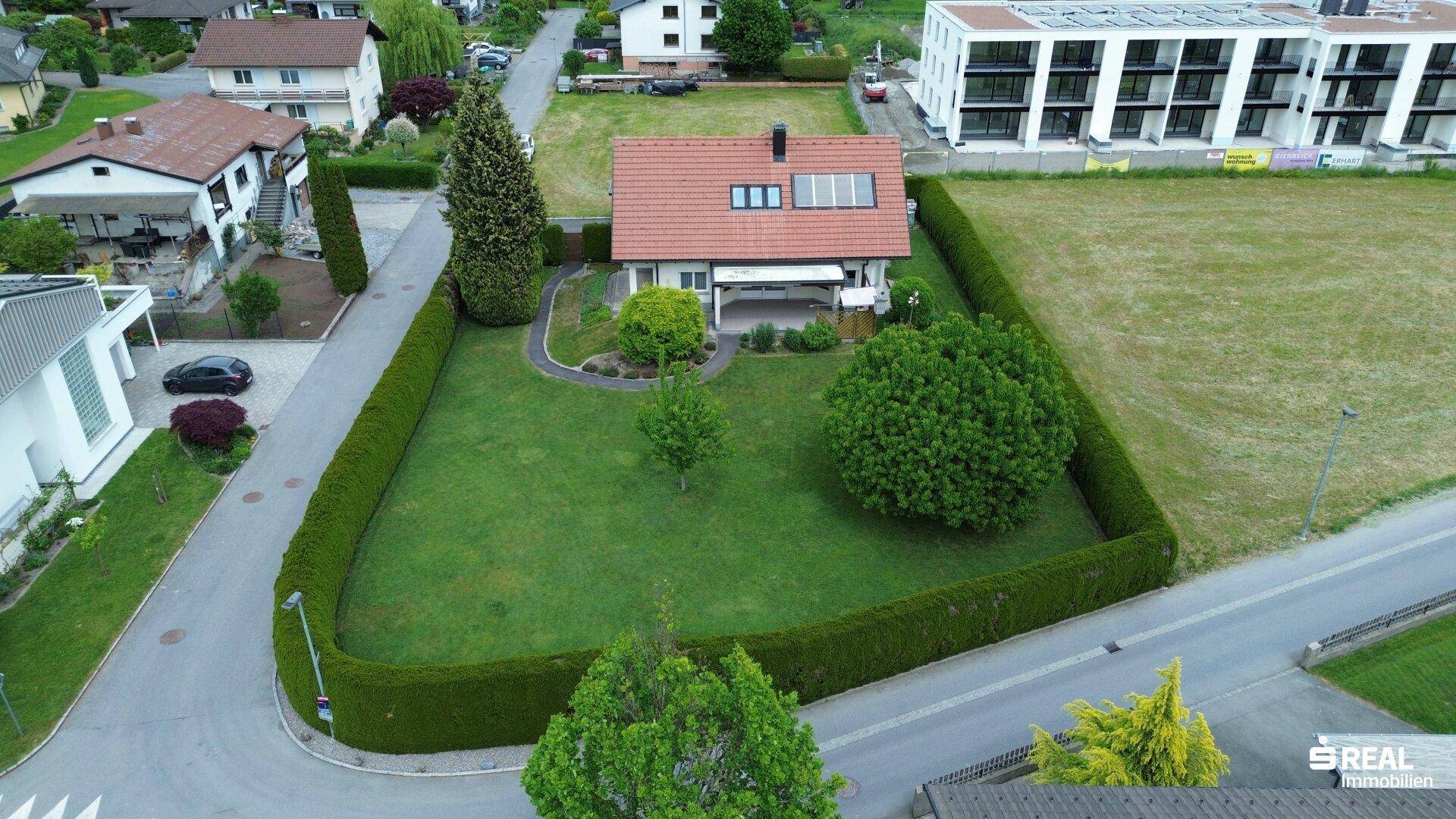 Luftaufnahme des Hauses mit großem Garten, umgeben von Hecken und Nachbargebäuden.