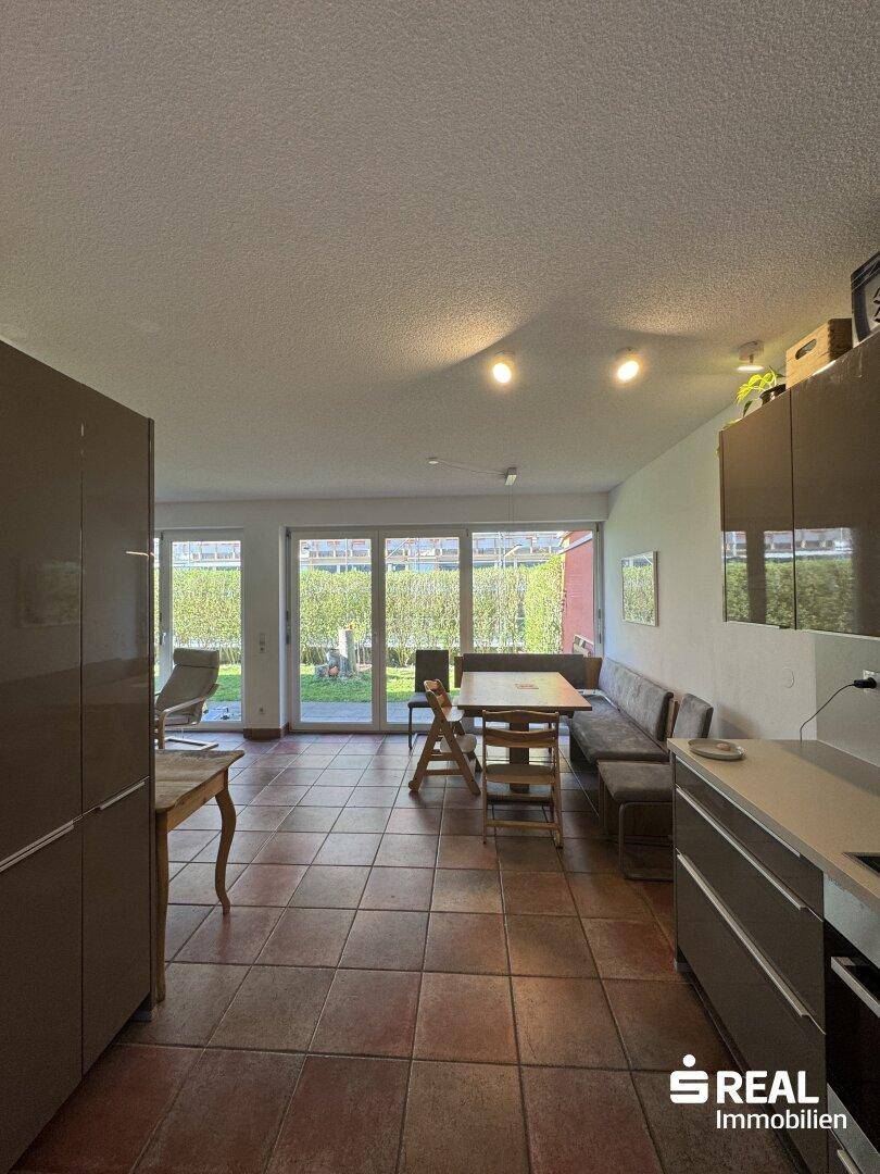 Helle Wohnküche mit Zugang zum Garten und Blick ins Grüne.