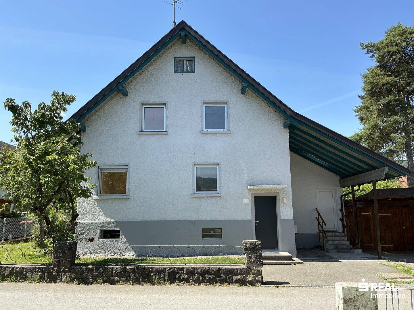 Vorderansicht des Einfamilienhauses mit Satteldach und Carport auf der rechten Seite.
